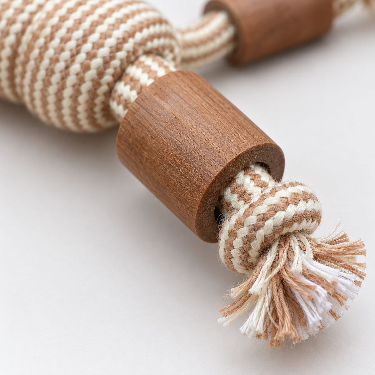 Natural cotton rope dog toy with decorative wooden beads on a white background.