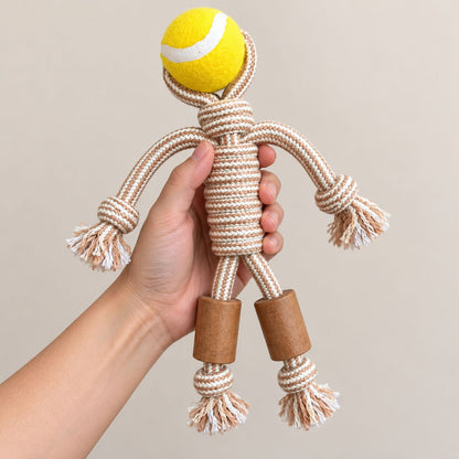 Hand holding a rope dog toy with a yellow tennis ball head and wooden legs.